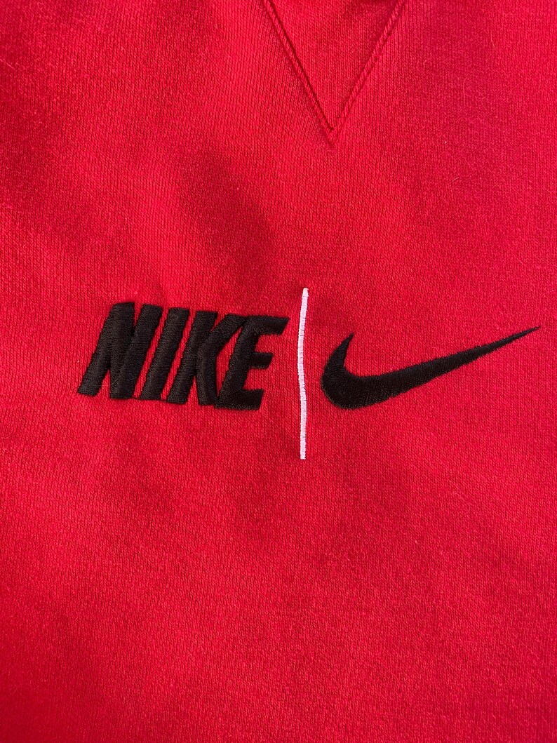 May include: Red sweatshirt with a black embroidered Nike logo and a white vertical line.