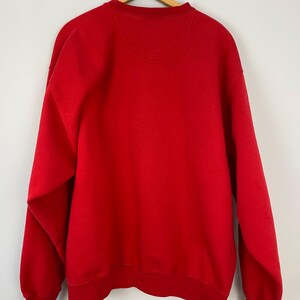 May include: A red crew neck sweatshirt with long sleeves.