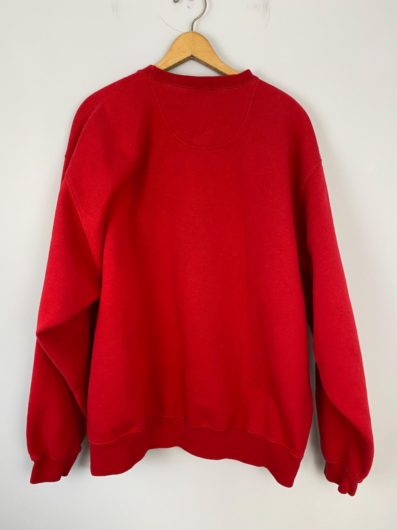 May include: A red crew neck sweatshirt with long sleeves.