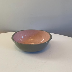 Op de afbeelding: Een kleine, ovale kom met een lichtgrijze buitenkant en een roze binnenkant. De kom heeft een gespikkelde glazuur.
