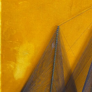 May include: A string art piece with a geometric design. The art is made with black thread and blue beads, and is mounted on a yellow velvet background.