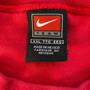 May include: A black and white tag with the Nike swoosh logo and the word "TEAM" in white lettering. The tag also includes the size "XXL TTG EEC" and the text "MADE IN MEXICO FABRIQUE AU MEXIQUE".