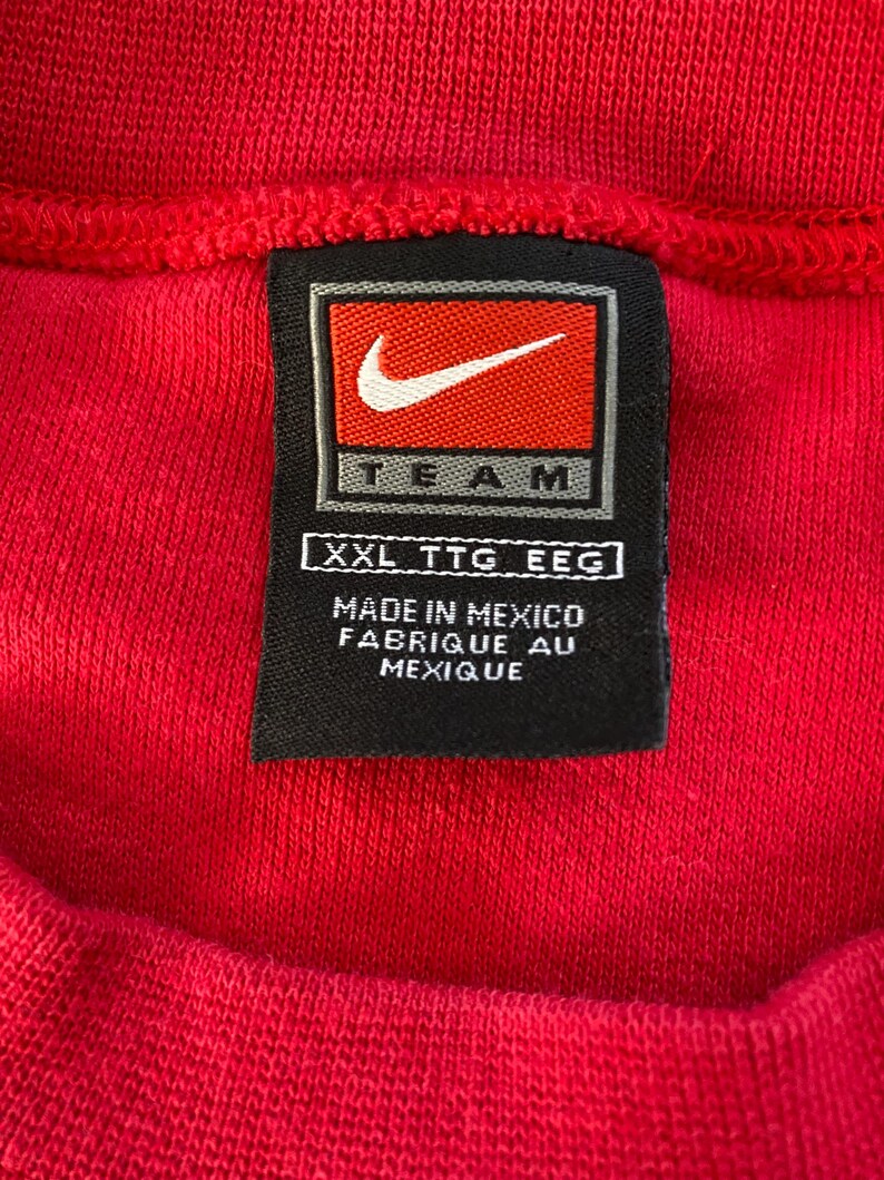 May include: A black and white tag with the Nike swoosh logo and the word "TEAM" in white lettering. The tag also includes the size "XXL TTG EEC" and the text "MADE IN MEXICO FABRIQUE AU MEXIQUE".