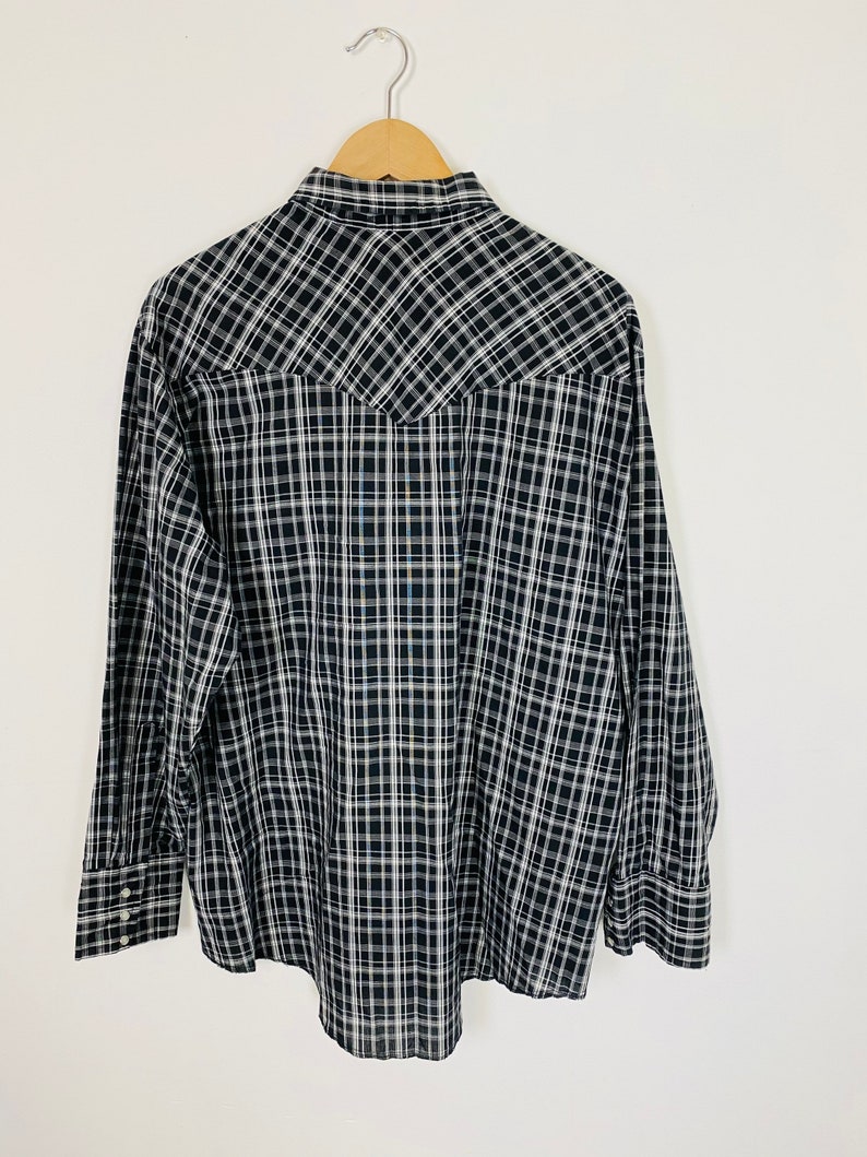 May include: A black and white plaid long-sleeve shirt with a pointed collar and button closure.