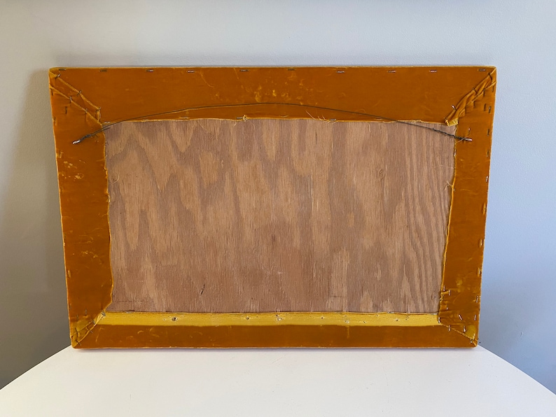 May include: The back of a rectangular picture frame with a gold velvet border. The frame is made of wood and has a wire hanger attached to the back.