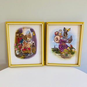 May include: Two framed illustrations, one depicting a mouse in a regal setting, the other a rabbit playing a drum. Both frames are yellow with a white border.