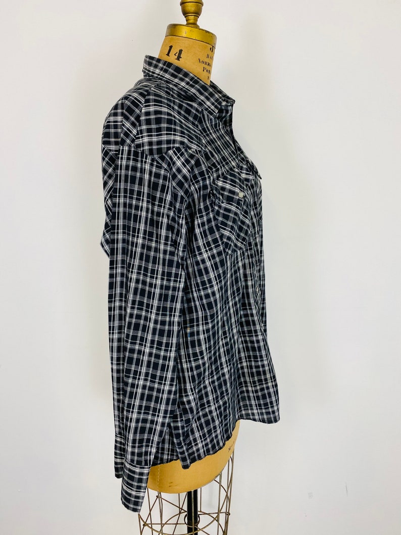 May include: A black and white plaid long-sleeved button-up shirt with a single chest pocket.