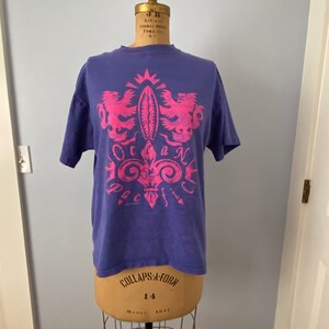 May include: A purple t-shirt with a pink graphic design of a crest with two birds and the text "Ocean Pacific".