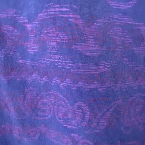 May include: Purple fabric with a textured pattern of swirls and lines.