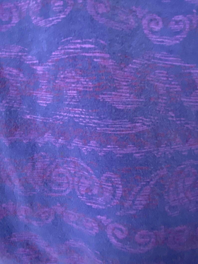 May include: Purple fabric with a textured pattern of swirls and lines.