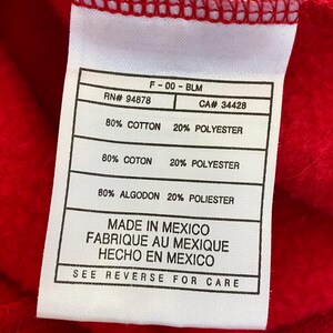 May include: White tag with black text detailing the fabric composition of a red sweatshirt. The tag reads "F-00-BLM", "RN# 94878", "CA# 34428", "80% COTTON 20% POLYESTER", "80% COTON 20% POLYESTER", "80% ALGODON 20% POLIESTER", "MADE IN MEXICO", "FABRIQUE AU MEXIQUE", "HECHO EN MEXICO", and "SEE REVERSE FOR CARE".