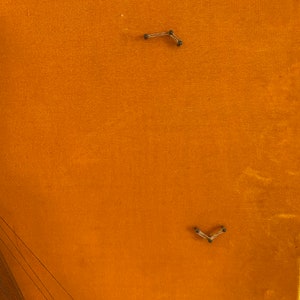 May include: A close-up of a piece of orange fabric with two small metal clips attached to it.