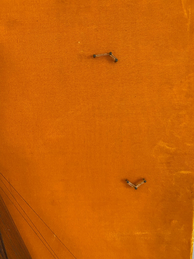 May include: A close-up of a piece of orange fabric with two small metal clips attached to it.