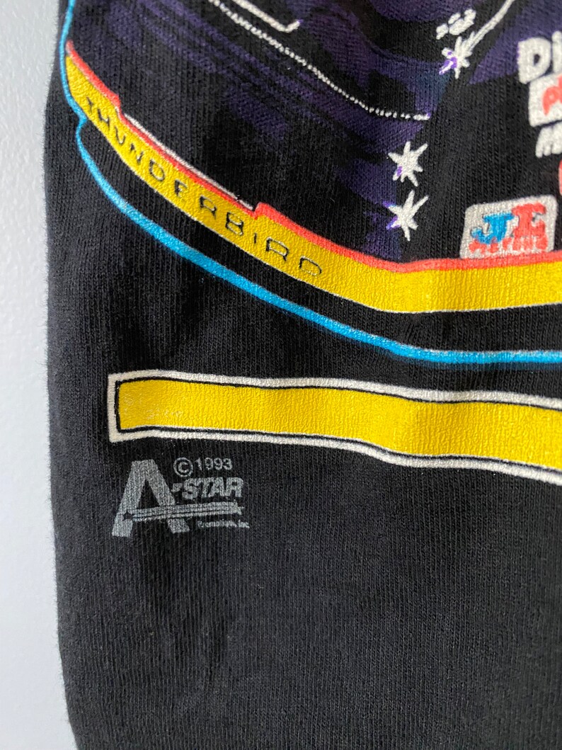 May include: Black t-shirt featuring a colourful graphic of a spaceship with the text "Thunderbird" and stars. The bottom of the shirt has a white and yellow stripe and the text "&copy;1993 A-STAR Canada, Inc."