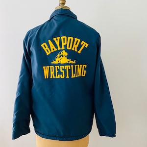 May include: A dark blue jacket with a yellow embroidered logo that says "Bayport Wrestling" with a graphic of two wrestlers.
