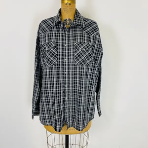 May include: A black and white plaid long-sleeved shirt with a button-down collar and two chest pockets.