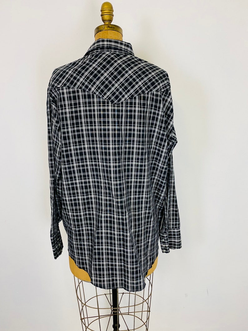 May include: A black and white plaid long-sleeve shirt with a pointed yoke in the back.
