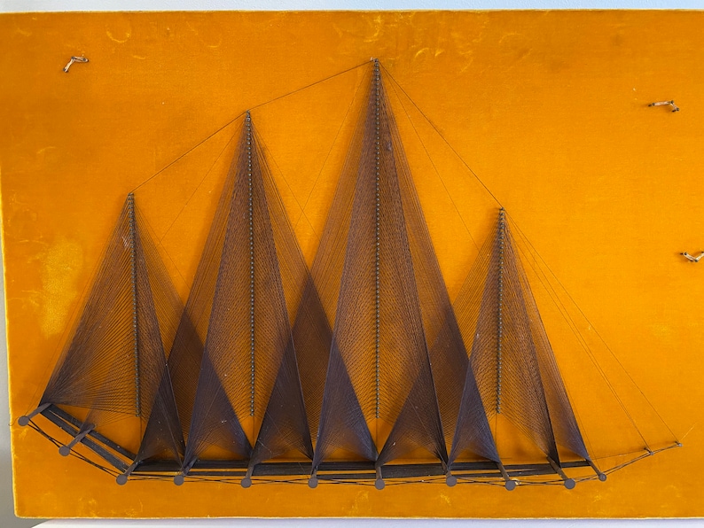 May include: A wall hanging made of string art depicting a series of triangles on a yellow background.