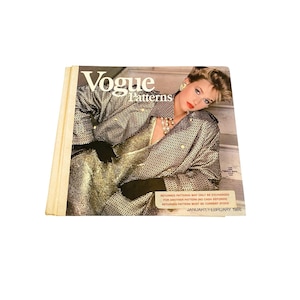 Op de afbeelding: Een vintage Vogue Patterns-magazinecover met een vrouw die een zwart-wit gepatroneerd jasje en een gouden jurk draagt. De tekst op de omslag luidt "Vogue Patterns" en "januari/februari 1986".