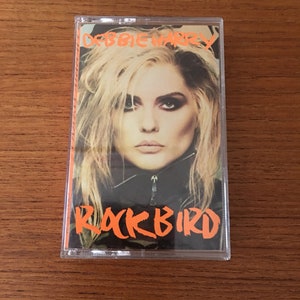 May include: A cassette tape with a clear plastic case. The front of the tape features a photo of Debbie Harry, the lead singer of Blondie, with the title "Rockbird" in orange text.