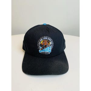 Pode incluir: Boné de beisebol preto e azul com um logotipo de um jogador de hóquei de desenho animado com o texto "Jacks Cleveland" nele.