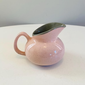 Op de afbeelding: Een klein roze roomkannetje met een gespikkeld glazuur en een grijze rand.
