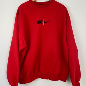 May include: Red vintage Nike sweatshirt with a black embroidered logo that says "NIKE" with a swoosh.
