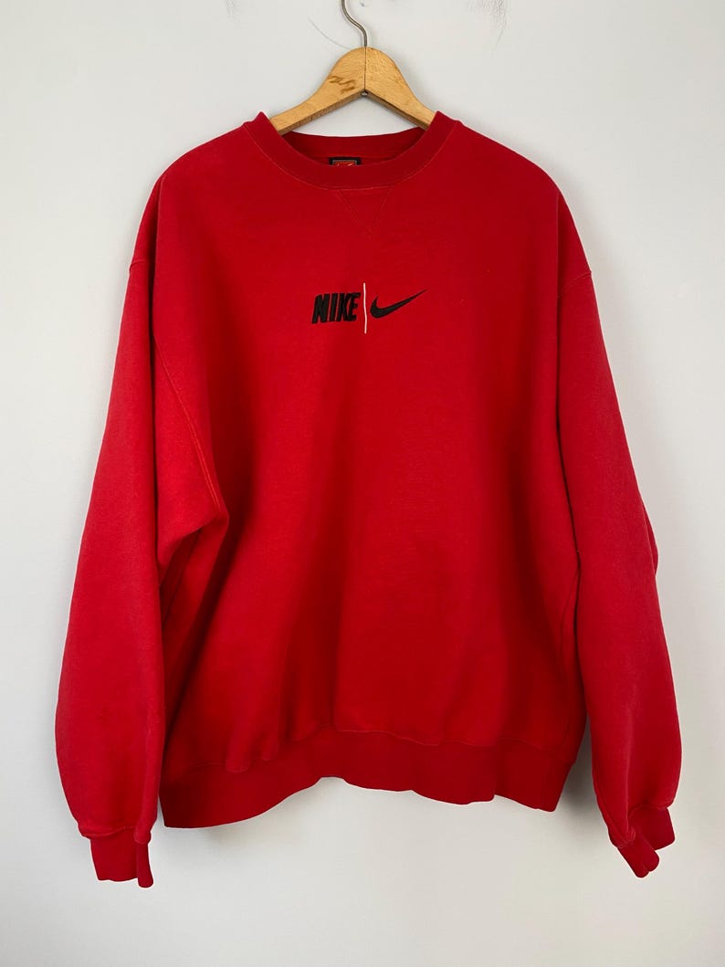 May include: Red vintage Nike sweatshirt with a black embroidered logo that says "NIKE" with a swoosh.