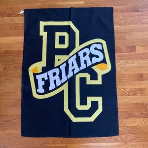 Puede incluir: Bandera negra con un gran logotipo amarillo "PC" y una pancarta amarilla con la palabra "FRIARS" en letras blancas.