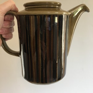 Puede incluir: Una cafetera de cer&aacute;mica rayada en marr&oacute;n y negro con asa y pico.