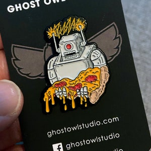 Puede incluir: Un robot blanco con ojos rojos sosteniendo una rebanada de pizza que gotea. El robot tiene antenas con rayos en la parte superior. El fondo es negro con el texto "Ghost Owl Studio" y la dirección del sitio web "ghostowlstudio.com".