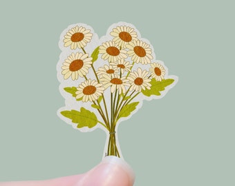 May include: A bouquet of white daisies with yellow centers, tied together with a brown string. The daisies are arranged in a fan shape, with the stems pointing down.