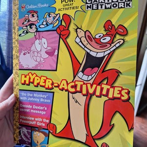 May include: A children's activity book featuring characters from Cartoon Network. The cover has a yellow background with the words "HYPER-ACTIVITIES" and "CARTOON NETWORK." The book includes activities with Johnny Bravo, Dexter, and the Powerpuff Girls.
