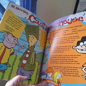 May include: Open book with colorful illustrations from "Ed, Edd n Eddy." The page features cartoon characters and text, including "Castle Clubhouse" in large letters. The text describes how to build a clubhouse.