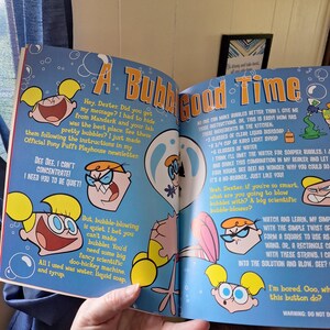 May include: A colorful page from a Dexter's Laboratory comic book. The page features cartoon illustrations of Dexter and Dee Dee, along with bubble-blowing instructions. Text includes the title "A Bubble Good Time."