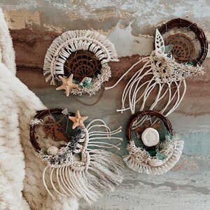 May include: Four handmade macrame wall hangings with a beach theme. Each hanging features a different design, including a seahorse, a turtle, a seashell, and a starfish. The hangings are made with natural fibers and have a rustic, bohemian style.