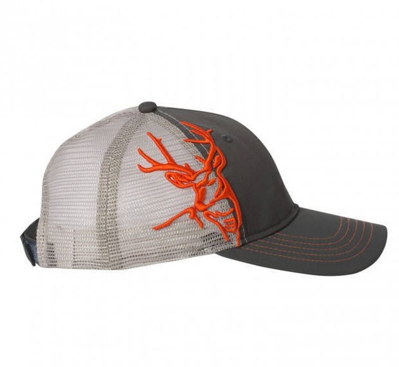 May include: A gray and white mesh baseball cap with an orange embroidered deer head design. The cap has a curved brim and a mesh back.