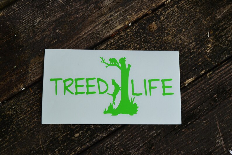 May include: A white sticker with a green silhouette of a tree with a bird and a dog on it. The text "TREE LIFE" is written in green below the tree.