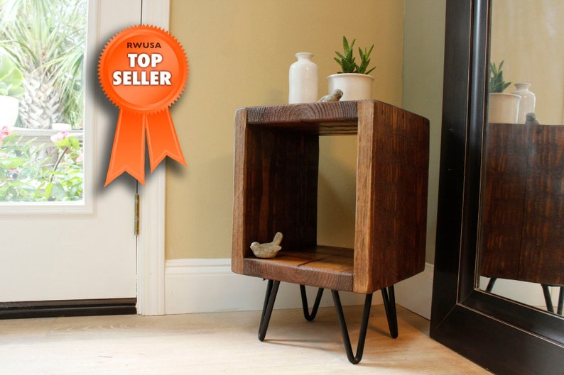 May include: A dark brown wooden end table with a single shelf and black hairpin legs. The table is sitting on a light brown wood floor.