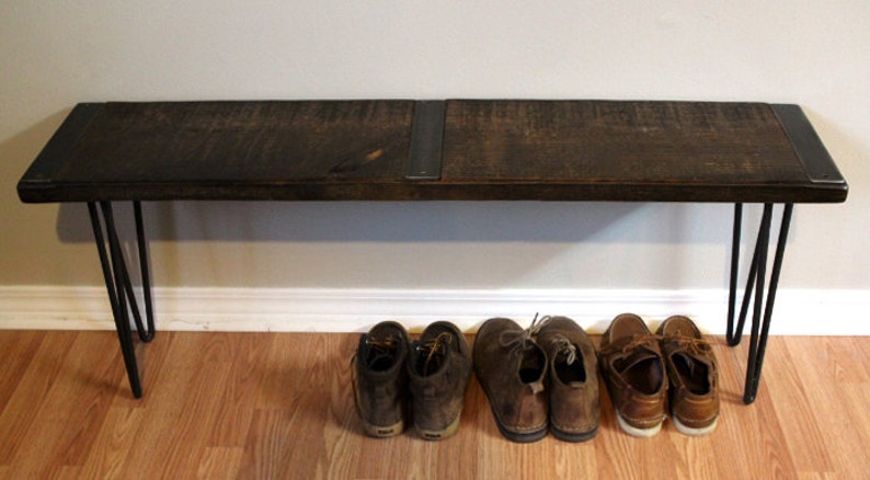 May include: A dark brown wooden bench with black metal hairpin legs. The bench is sitting on a wooden floor and has a pair of brown leather shoes underneath.