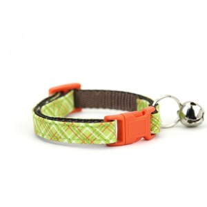 May include: A green and orange patterned cat collar with a brown adjustable strap and a silver bell.