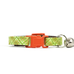 May include: A green and orange plaid cat collar with an orange plastic buckle and a silver bell.