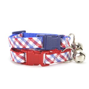Puede incluir: Un collar para gato de cuadros rojos y azules con una campanilla. El collar tiene un cierre de hebilla de pl&aacute;stico.