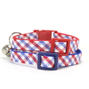 Puede incluir: Dos collares de gato de cuadros rojos y azules con hebillas de pl&aacute;stico ajustables. Los collares est&aacute;n superpuestos.