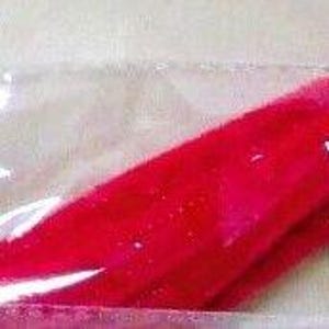 May include: Bright red, ribbon-like sweets are sealed in a clear plastic wrapper. The sweets appear to be a twisted shape, with a glossy finish. The image is a close-up of the sweets.
