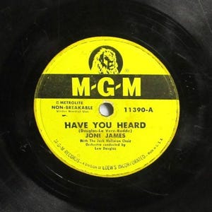 May include: A vintage vinyl record with a yellow and black label. The label features the text "M-G-M" and "HAVE YOU HEARD" by Joni James. The record is a 7-inch disc, a classic music format.
