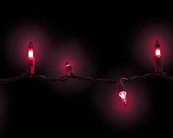 May include: A string of small, glowing red incandescent lights connected by a dark wire. The individual bulbs emit a vibrant crimson light against a dark background, creating a series of illuminated points along the horizontal wire strand.