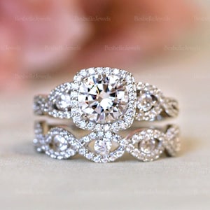 May include: A dazzling diamond engagement ring set. The ring features a large, square-cut center stone surrounded by a halo of smaller diamonds. The band is also adorned with diamonds, creating a sparkling effect. The set includes a matching wedding band.