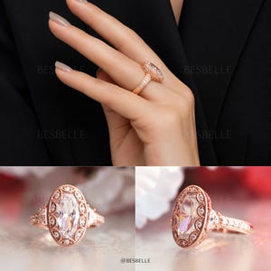 May include: A rose gold ring featuring a central marquise-cut clear stone surrounded by a halo of smaller round stones. The band and setting include intricate milgrain detailing. The text BESBELLE is visible on the image background.