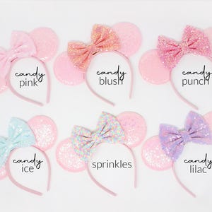 May include: Six headbands with round ears and bows, each featuring different sequin colors and textures. The text labels are candy pink, candy blush, candy punch, candy ice, sprinkles, and candy lilac, displayed next to each corresponding headband.